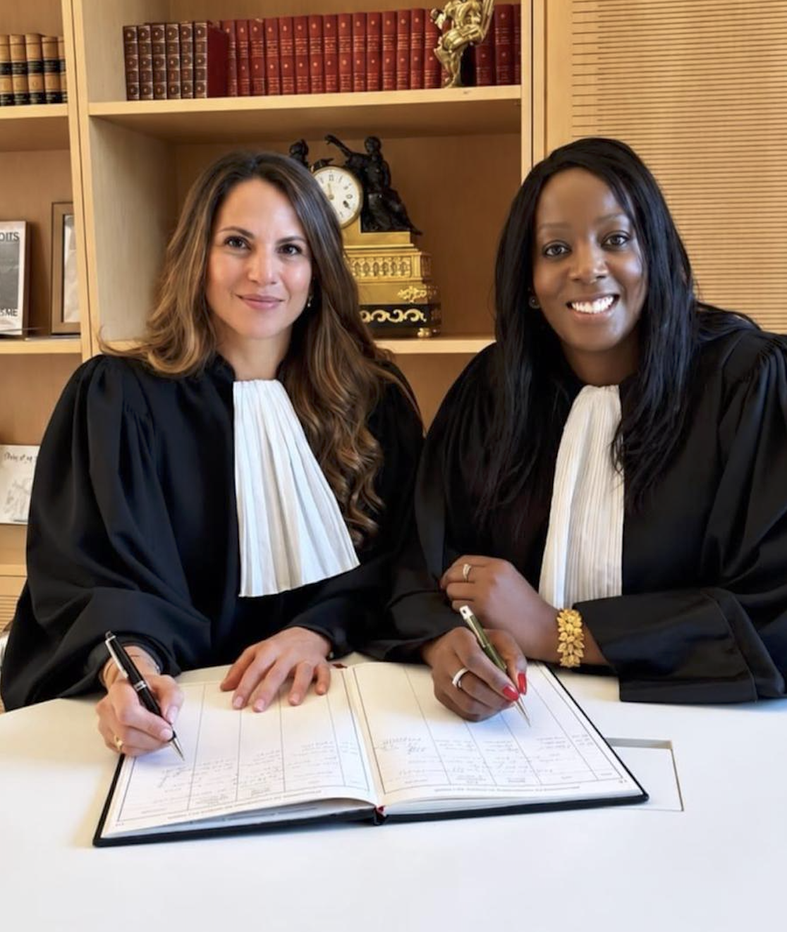 Clarisse Surin et Merav Griguer, en robe d’avocate, réunies autour d’un registre